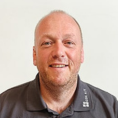 Portraitfoto eines Mannes mit grauem Poloshirt.