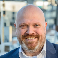 Lars Klippert, Mann mit Glatze und Vollbart. blaues Jacket und weißes Hemd.