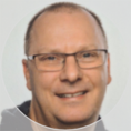 Portraitfoto eines lächelnden Mannes mit Brille.